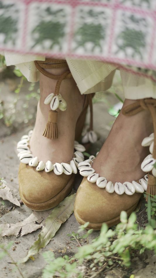 Photo of Beige suede pumps (heels) with ankle strap and sea shell detailings.